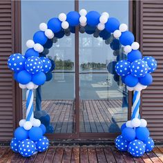 a blue and white balloon arch with polka dot balloons in front of a glass door