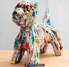 a dog made out of clothes pegs on a wooden table next to a white wall