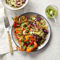 two plates with salad on them next to silverware