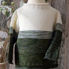 a green and white sweater sitting on top of a wooden table