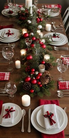 the table is set for christmas dinner with red and white napkins, silverware, candlesticks and pine cones