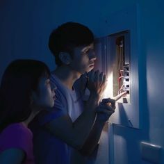 two people are looking at an electrical panel in the dark, while one person is using a light switch