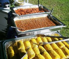 corn on the cob and other foods are lined up in trays