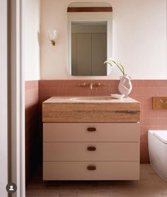 a bathroom with pink and white tiles on the walls, sink and mirror above it