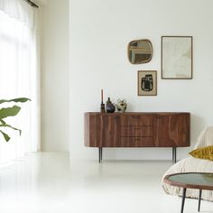 a living room with white walls and wooden furniture in the corner, along with pictures on the wall