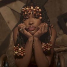 a woman with her hands on her face and beads around her neck, posing for the camera