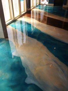 the floor is covered in blue and white water, reflecting light from windows on either side