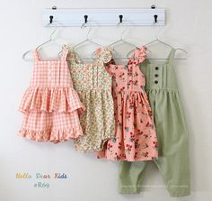 three baby girls'dresses hanging on a clothes rack with pegs in front of them