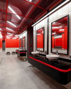 a public restroom with sinks, mirrors and urinals on the walls in red and black colors