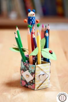 an origami pencil holder filled with colored pencils