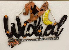 a metal sign that says halloween hanging on the side of a white wall with orange and black decorations