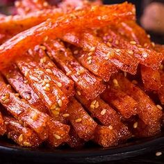 sliced meat on a black plate with sesame seeds