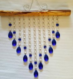 a blue and white beaded necklace hanging from a wooden hanger on a wall