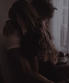 two women hugging each other in front of a window with the light coming through them