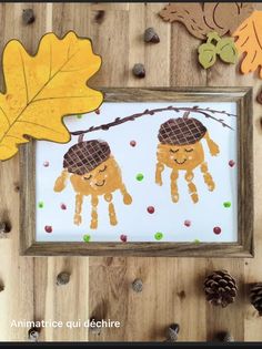 two handprints are hanging on a wooden frame with leaves and acorns