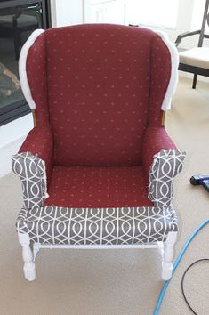 a red and white chair sitting in front of a fire place next to a fireplace