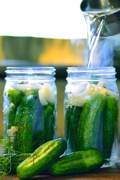 cucumbers and onions in mason jars with water pouring from a faucet