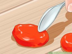 a person cutting tomatoes with a knife on a wooden surface next to them is another tomato that has been cut in half