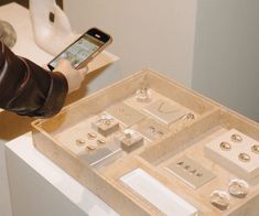 a person holding a cell phone and looking at jewelry on display