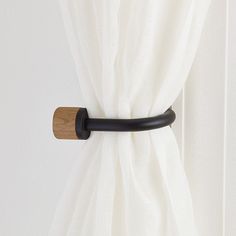 a curtain with a black handle hanging on it's side next to a white curtain