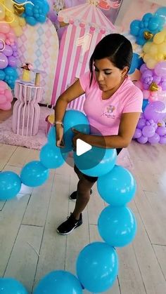 a woman in pink shirt sitting on floor next to blue and white balloon garlands