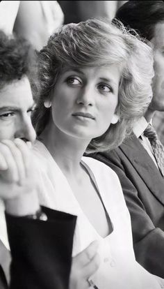 black and white photograph of two people sitting next to each other in front of a crowd