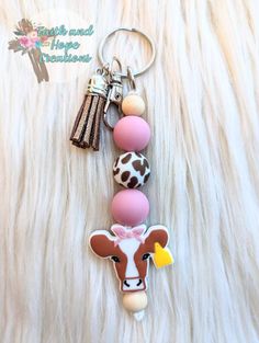 a keychain with a cow on it is sitting on a fur surface and has a tag attached to it