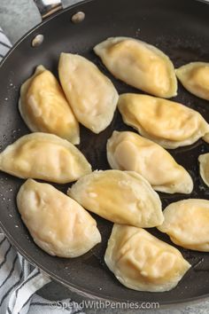 dumplings being cooked in a frying pan on a stove top with a towel