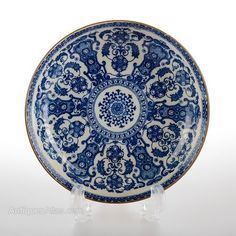 a blue and white plate sitting on top of a glass stand in front of a white background