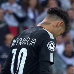 a male soccer player in a black uniform with his head turned to the side looking down