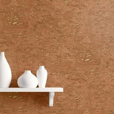 three white vases sitting on a shelf against a brown and tan wall with gold speckles