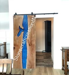 an open door to a room with wood floors and white walls that has a blue painting on it