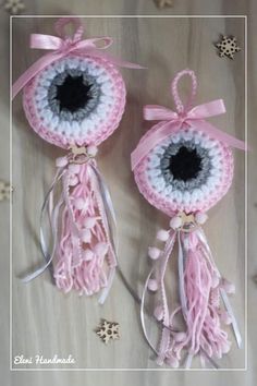 two pink and white crocheted ornaments with bows on them, one is in the shape of an eye