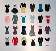 an assortment of doll clothes are displayed on a white surface in front of a wall