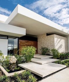 a modern house with plants and rocks in the front yard