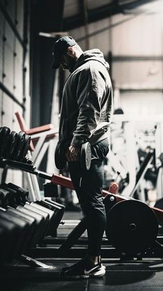 a man standing in front of a row of gym equipment with his hands on his hips