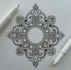 a pen and some ink sitting on top of a piece of paper with an ornate design