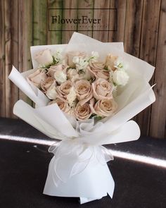 a bouquet of flowers sitting on top of a white ribbon tied to a wooden fence