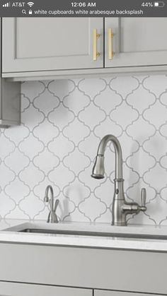 a kitchen sink with a faucet in the middle and white cabinets behind it