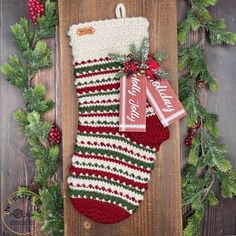 a christmas stocking hanging on a wooden board with two tags attached to the stockings