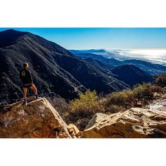 a man standing on top of a rock next to a mountain