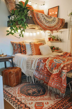 a bed with lots of pillows and blankets on top of it next to a potted plant