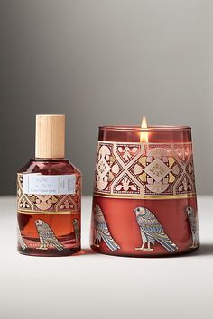 a candle that is sitting next to a jar with a bird design on the side