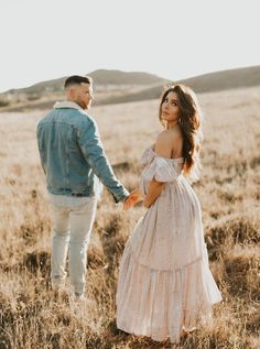 a man and woman holding hands in a field