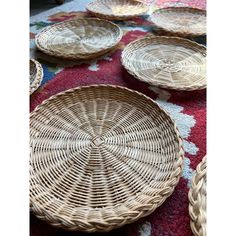 wicker baskets sitting on top of a red rug next to other woven items and bowls