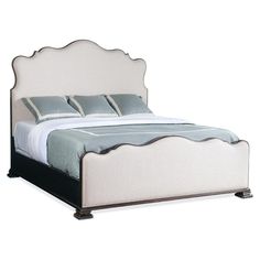 a bed with white linens and blue pillows on it's headboard, in front of a white background