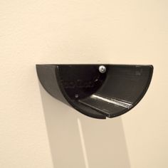 a black object mounted to the wall with a metal hook on it's side