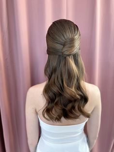 a woman with long hair in a white dress is looking at her back while wearing a half - up hairstyle