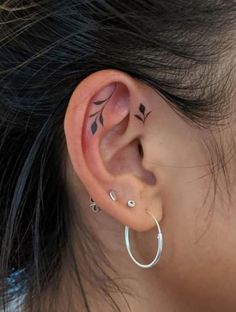 a woman's ear with small leaves on the inside of her nose and behind it is