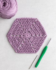 the crochet is next to some yarn and a ball of green knitting needles